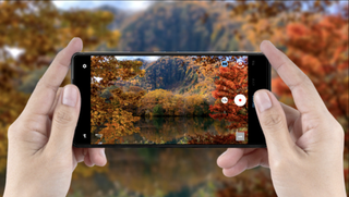 Sharp Leica Aquos R9 phone in hands taking photo of fall/autumn trees