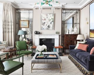 Formal living room ideas with a blue velvet sofa, antique dresser, fireplace with tarnished mirrors either side and green armchairs