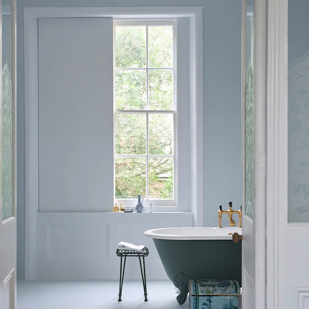 bathroom with pale blue walls and freestanding blue bath