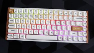 A Keychron K2 HE gaming keyboard with a wood finish and white keycaps with RGB enabled.