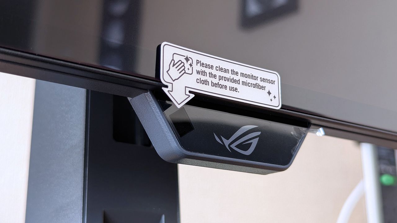 Close‑up of the ASUS ROG Strix OLED monitor&rsquo;s front sensor module attached beneath the display.