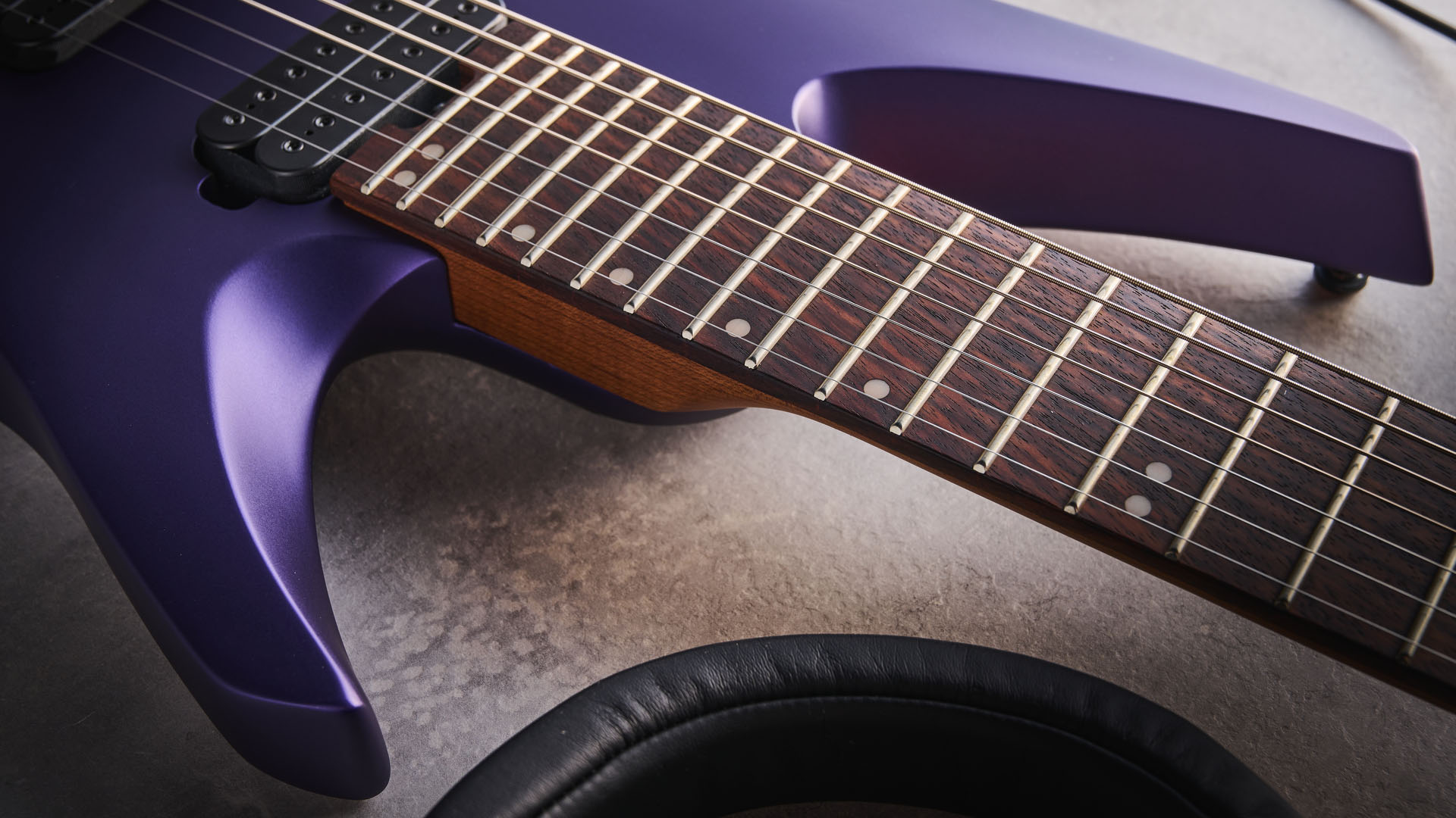 Sterling By Music Man Kaizen 7-string in Firemist Purple Satin, shot in close-up.