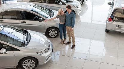 Young couple looking at new cars at a car dealership