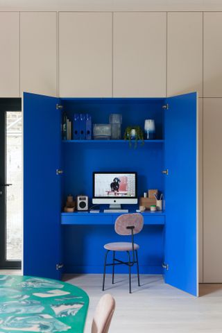 desk inside a blue cupboard with screen and storage