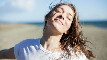 a woman on the beach smiling - best gradual tanners