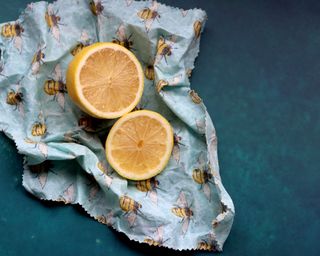 Lemon cut in half and colorful blue and yellow beeswax wrap underneath