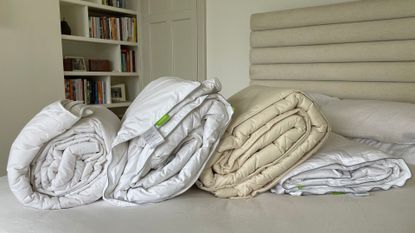 Four of the best duvets - the scooms down duvet, Silentnight half and half, Woolroom washable duvet, and IKEAs on a bed