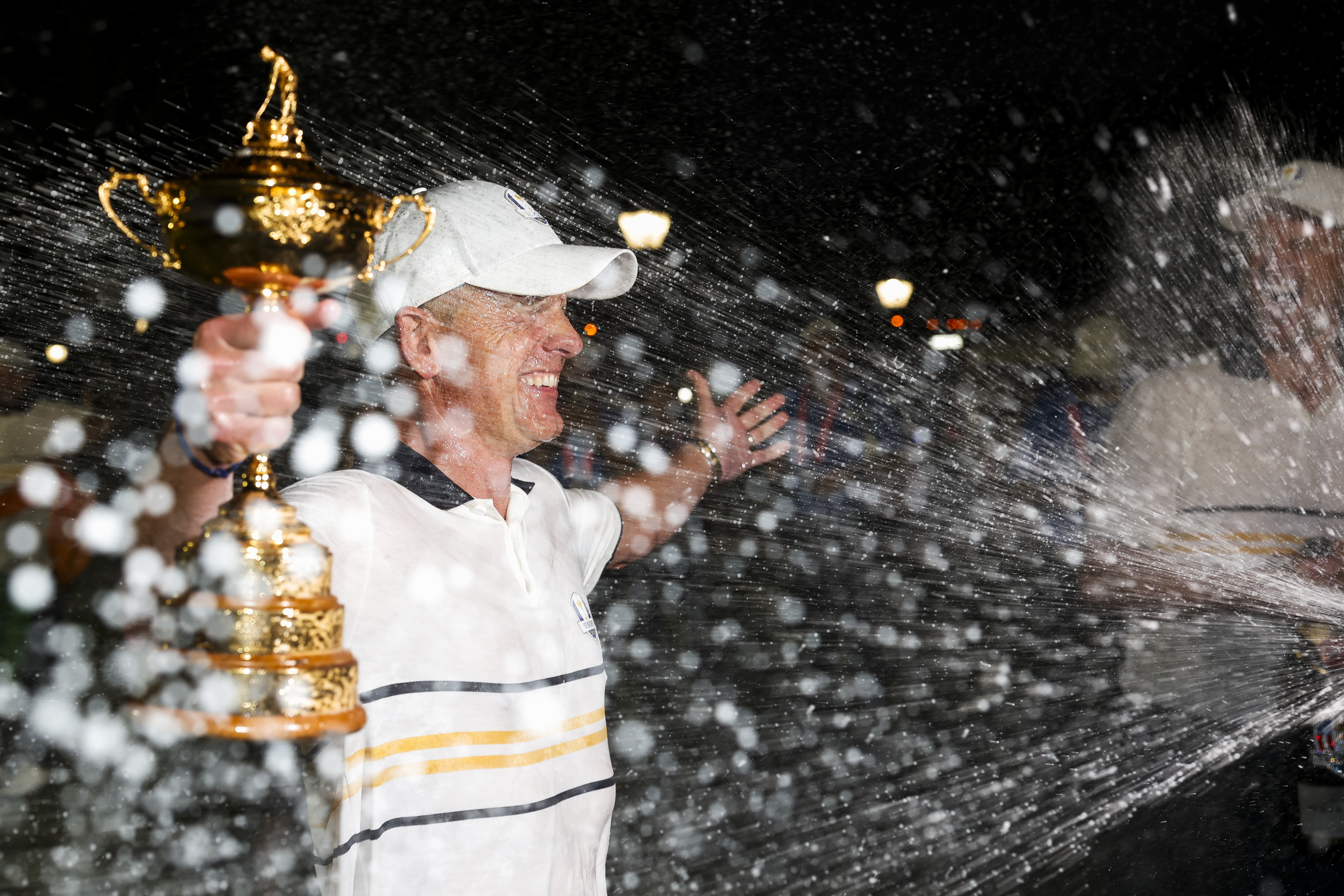 Luke Donald is sprayed with champagne while holding the Ryder Cup closest to the camera