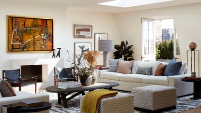 White living room with dark wood furniture, artwork above fireplace and gallery wall in alcove to the right