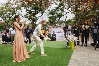 Meghan Markle wears a heidi merrick peach dress while in Nigeria with Prince Harry