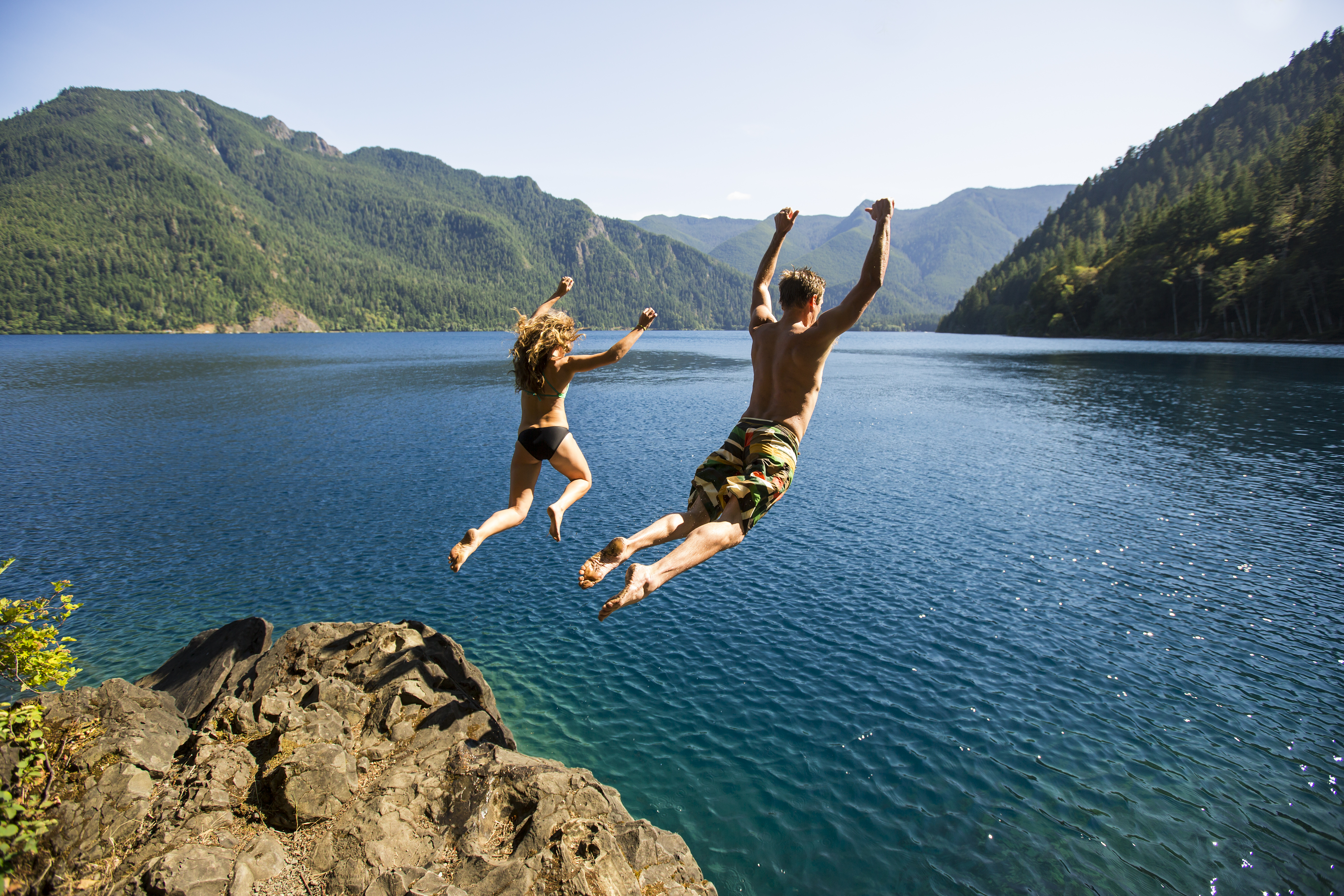 A man and a woman jump into a lake
