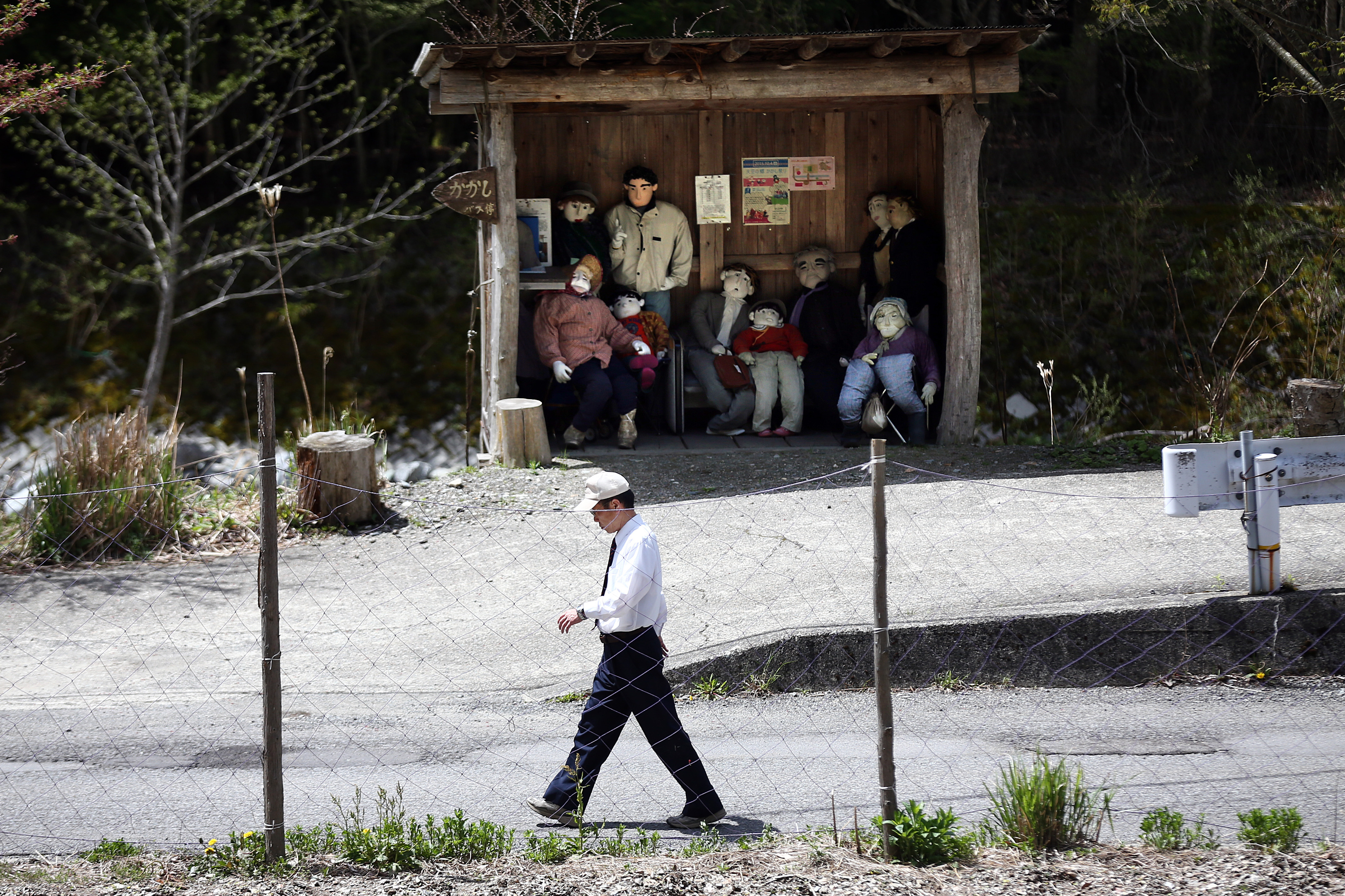 MIYOSHI, JAPAN - APRIL 22: A man walks past a shelter containing dolls that are hand-made and placed around the village by local resident Tsukimi Ayano to replace the dwindling local population
