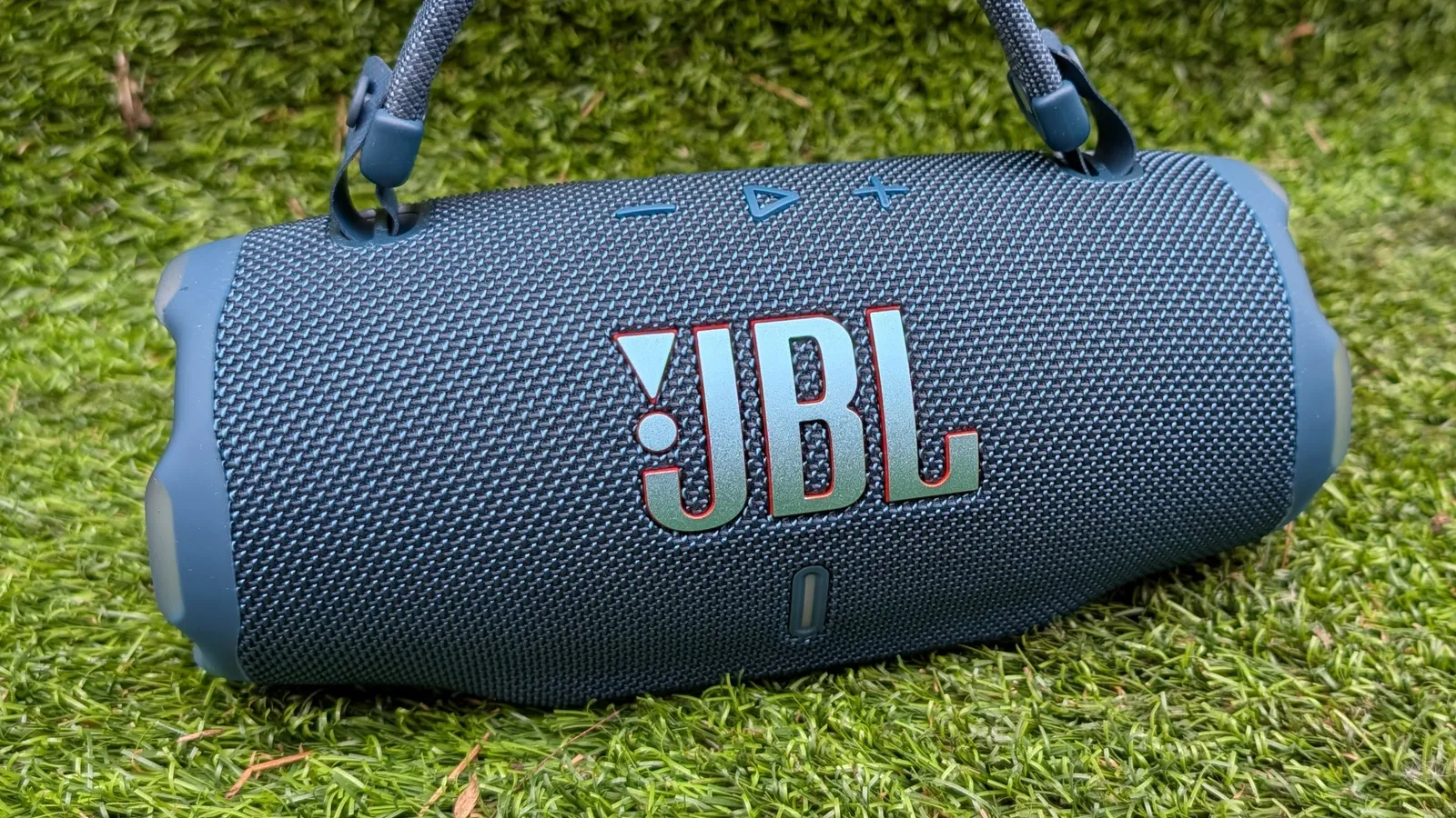 The JBL Charge 6 in blue on a green background.