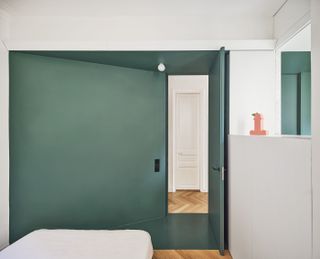 A bedroom with a dark green wall