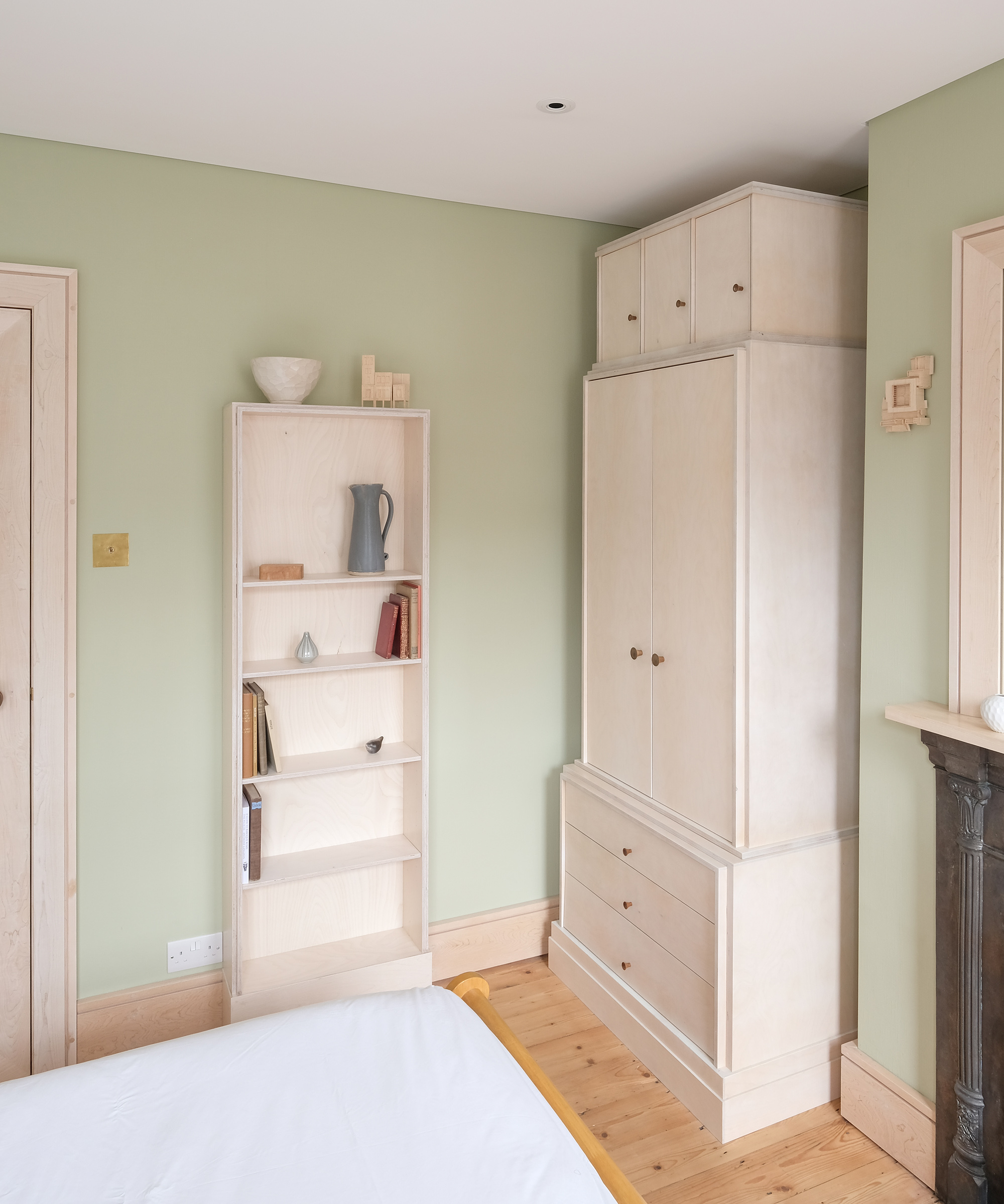 Birch plywood storage in a bedroom with pale green painted walls and wooden floors