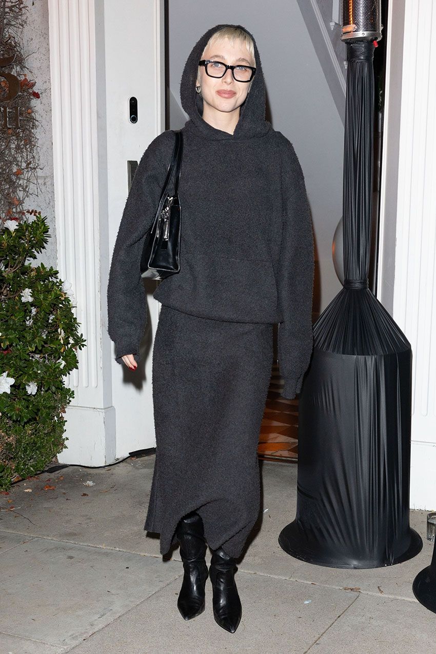 Emma Chamberlain wearing a gray knit set and slouchy black boots