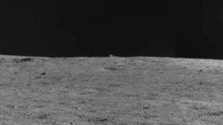 A cube-shaped object on the horizon of the moon's surface