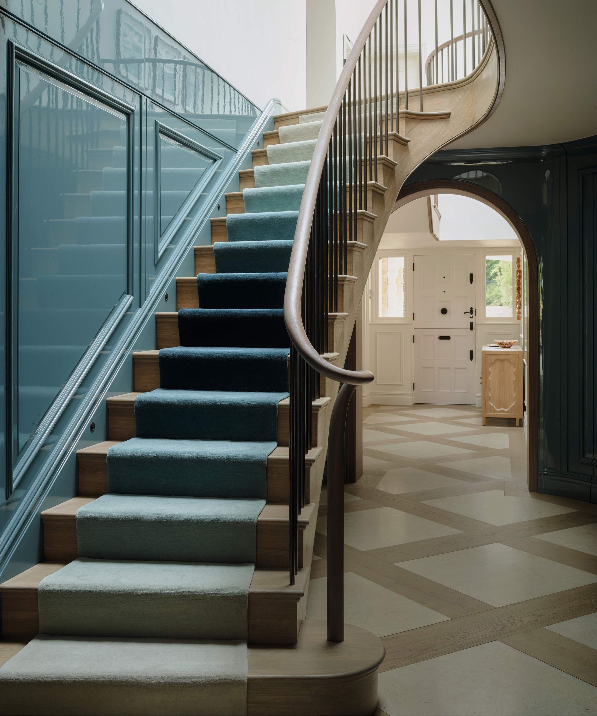 a curved staircase with blue gloss panelling and an ombre blue stair runner