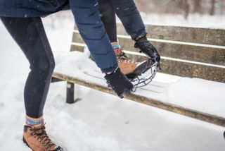 A hiker pulling on traction devices over hiking boots