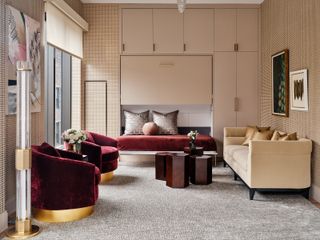 A living room with burgundy velvet seating and a murphy bed pulled out from the wall