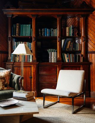 dark wood paneled room with bookshelves and chrome armchair