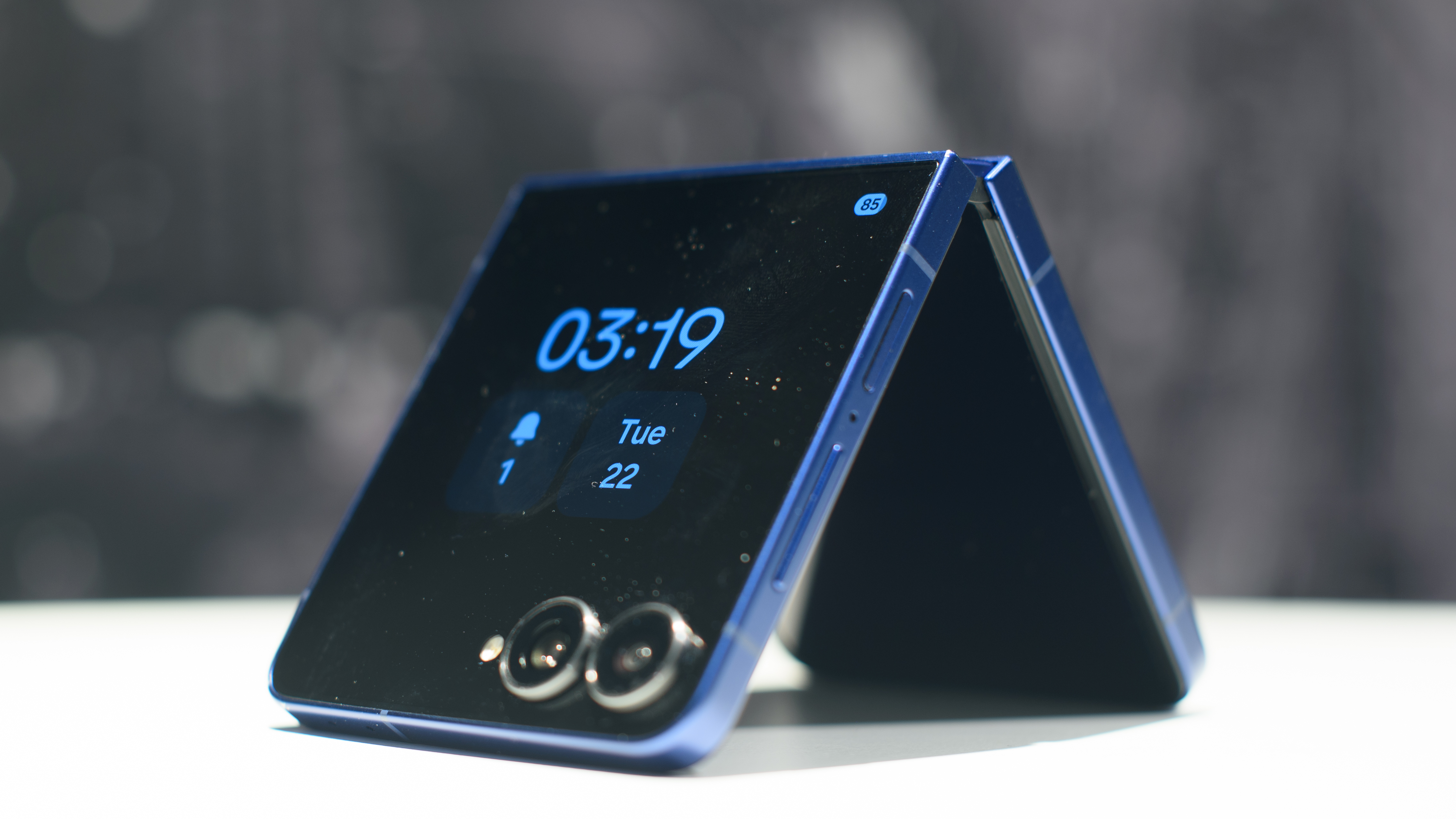 Samsung Galaxy Z Flip 7 in blue folded with the always-on display showing the time on the cover display