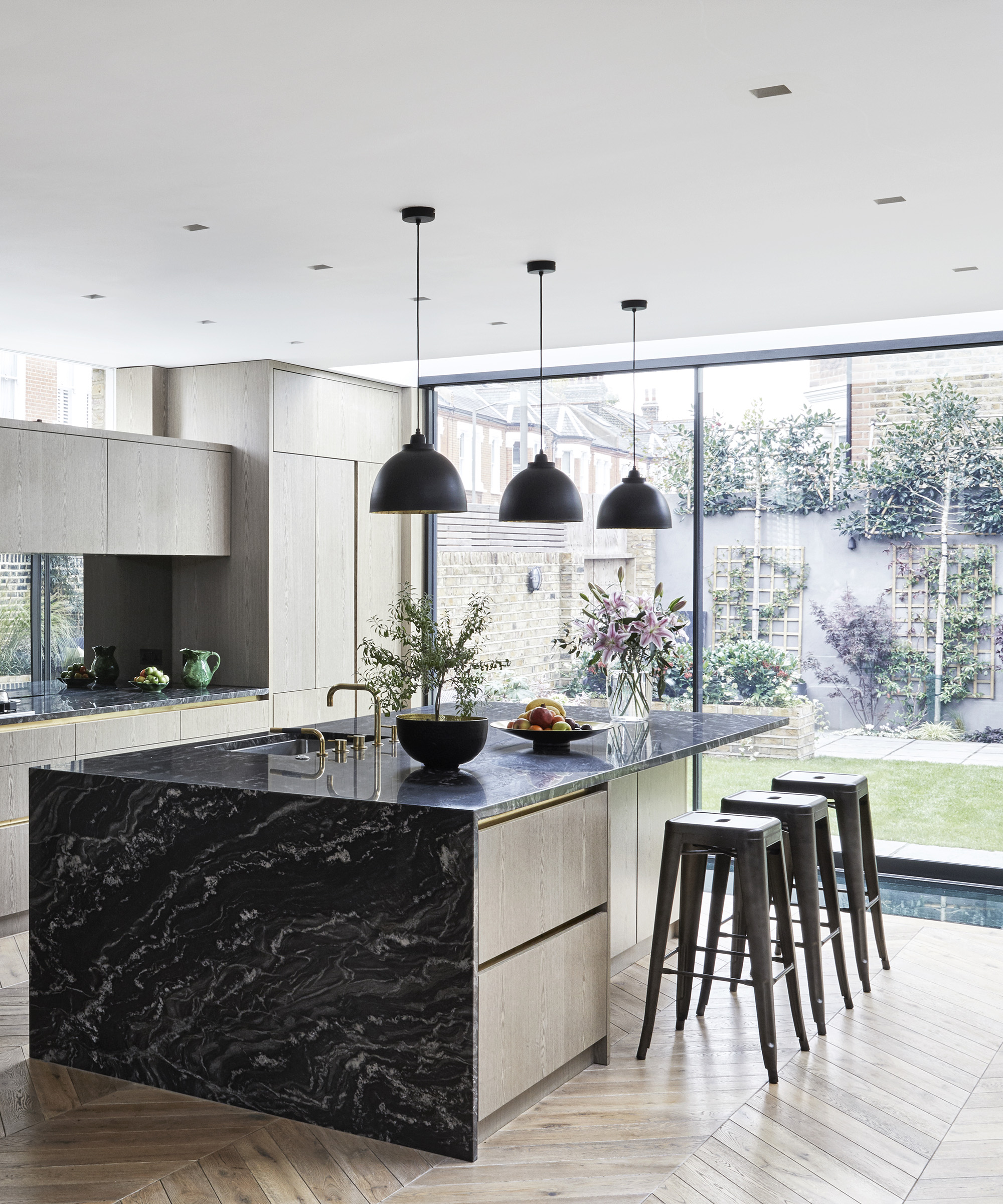 Black marble island with black bar stools and pendant lighting