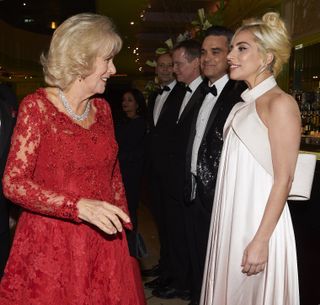 Camilla, Duchess of Cornwall reacts as she greets Robbie Williams (2ndR) and Lady Gaga during the Royal Variety Performance