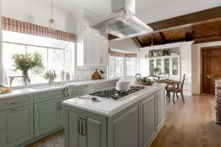 kitchen with green units, wooden floor, vaulted ceiling, dining table in background