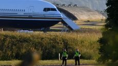 police officers in front of Boeing 767 on the runway at the military base in Amesbury