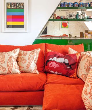 Small living room with red sofa in foreground and mirrored home bar in background