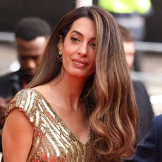 Amal Clooney wears a gold floor-length sequin gown at the King's Trust event red carpet