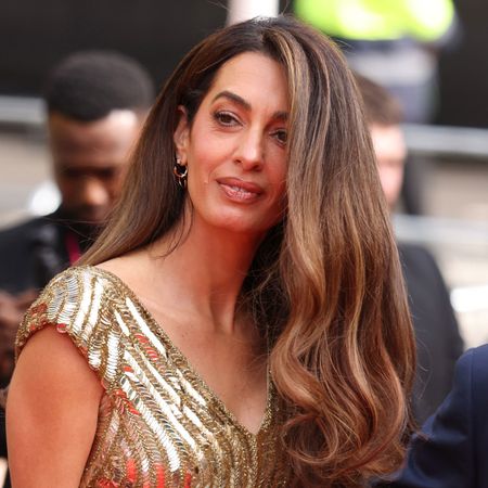 Amal Clooney wears a gold floor-length sequin gown at the King's Trust event red carpet