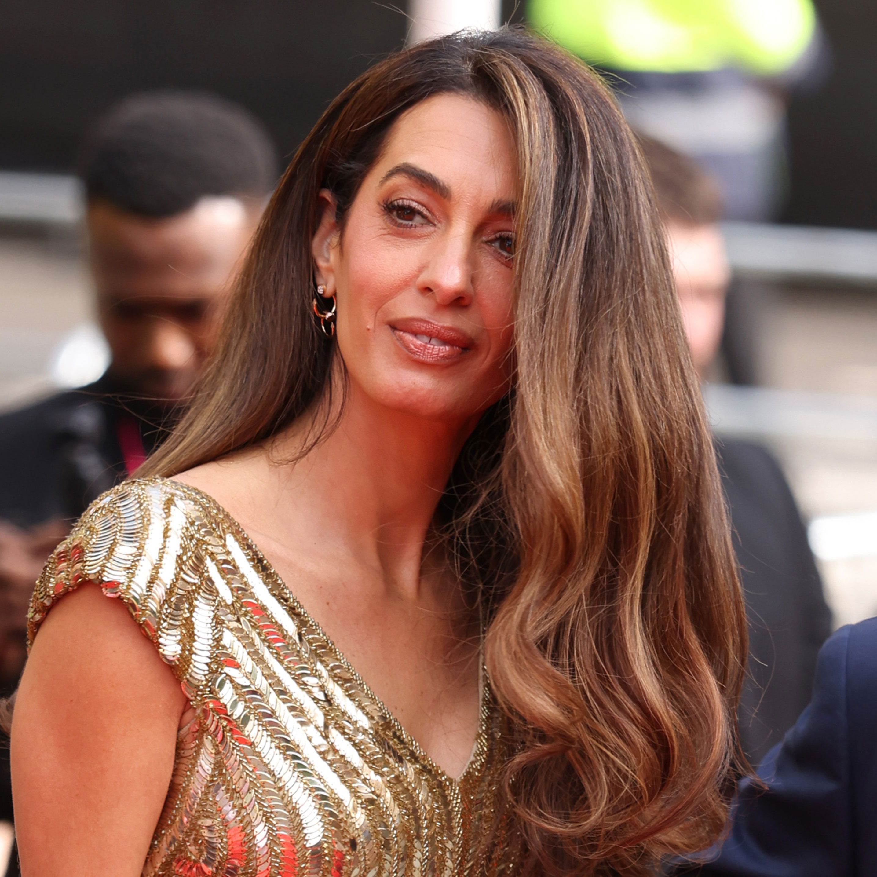 Amal Clooney wears a gold floor-length sequin gown at the King's Trust event red carpet
