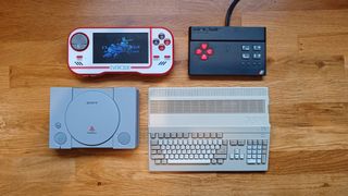 A collection of the best retro game consoles on a wooden table, including PlayStation, Amiga, ZX Spectrum and Evercade