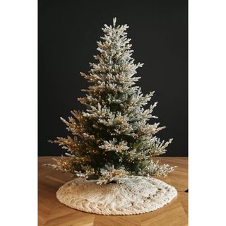 A knited cream tree skirt around the base of a realistic faux tree