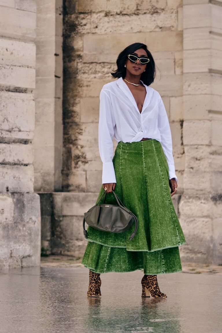 a woman wearing a white button down shirt and green skirt and cheetah boots