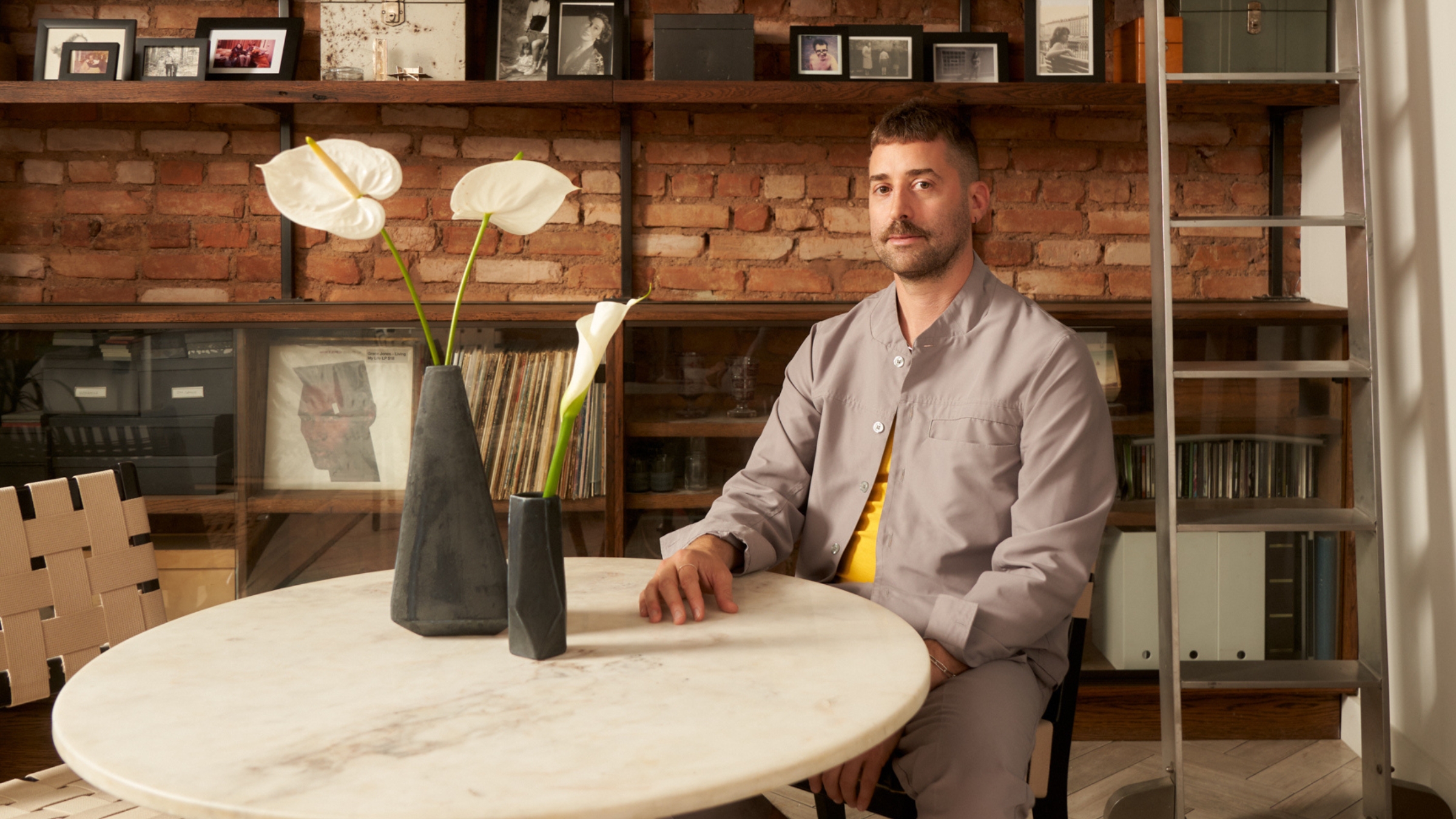 a man sitting at a dining table with flowers on in a loft apartment