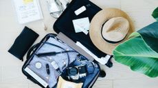 suitcase open on the floor with a sunhat, notebook and other packing