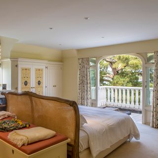 master bedroom with a balcony view and white curtains