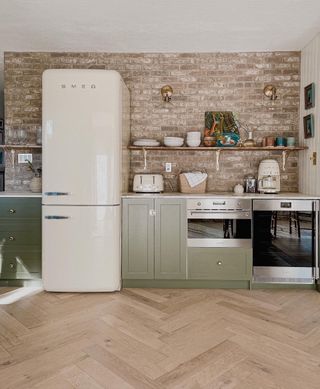 kitchen with exposed brick wall large cream fridge freezer and green cabinets with open shelves above