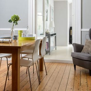 A grey dining room with wooden table and grey acrylic chairs on wooden floor