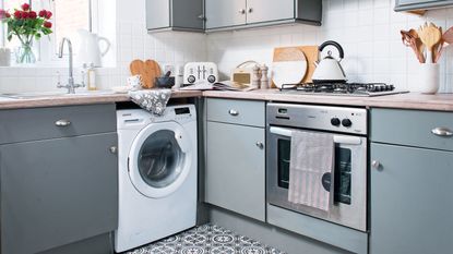 blue kitchen with oven, washing machine and kettle