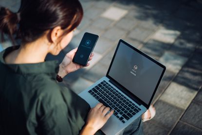 A woman using two-step authentication with her phone and laptop