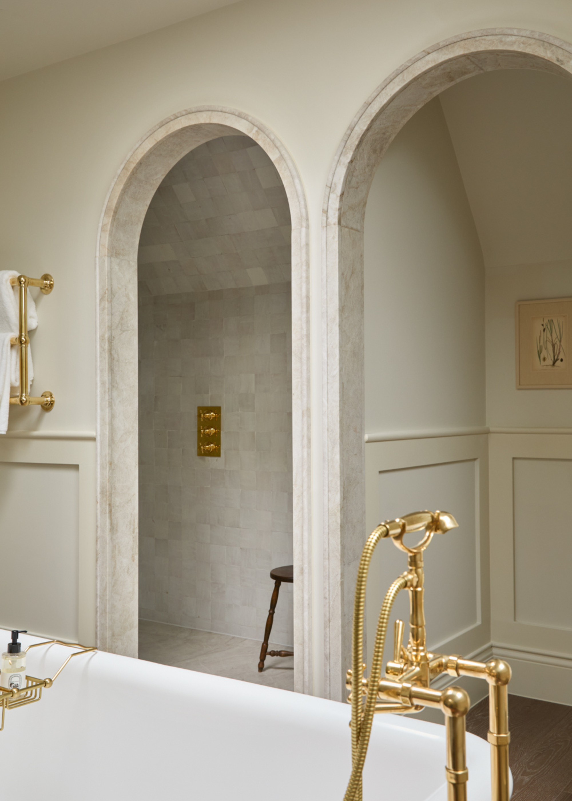 beautiful neutral bathroom with two marble lined arches and a freestanding bath