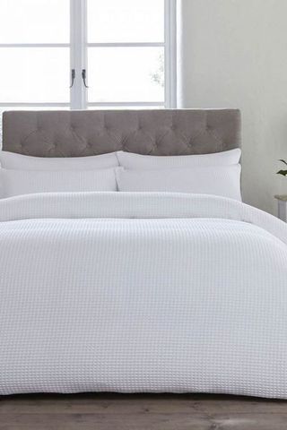 White portofino bedding set from DUSK on bed with grey headboard