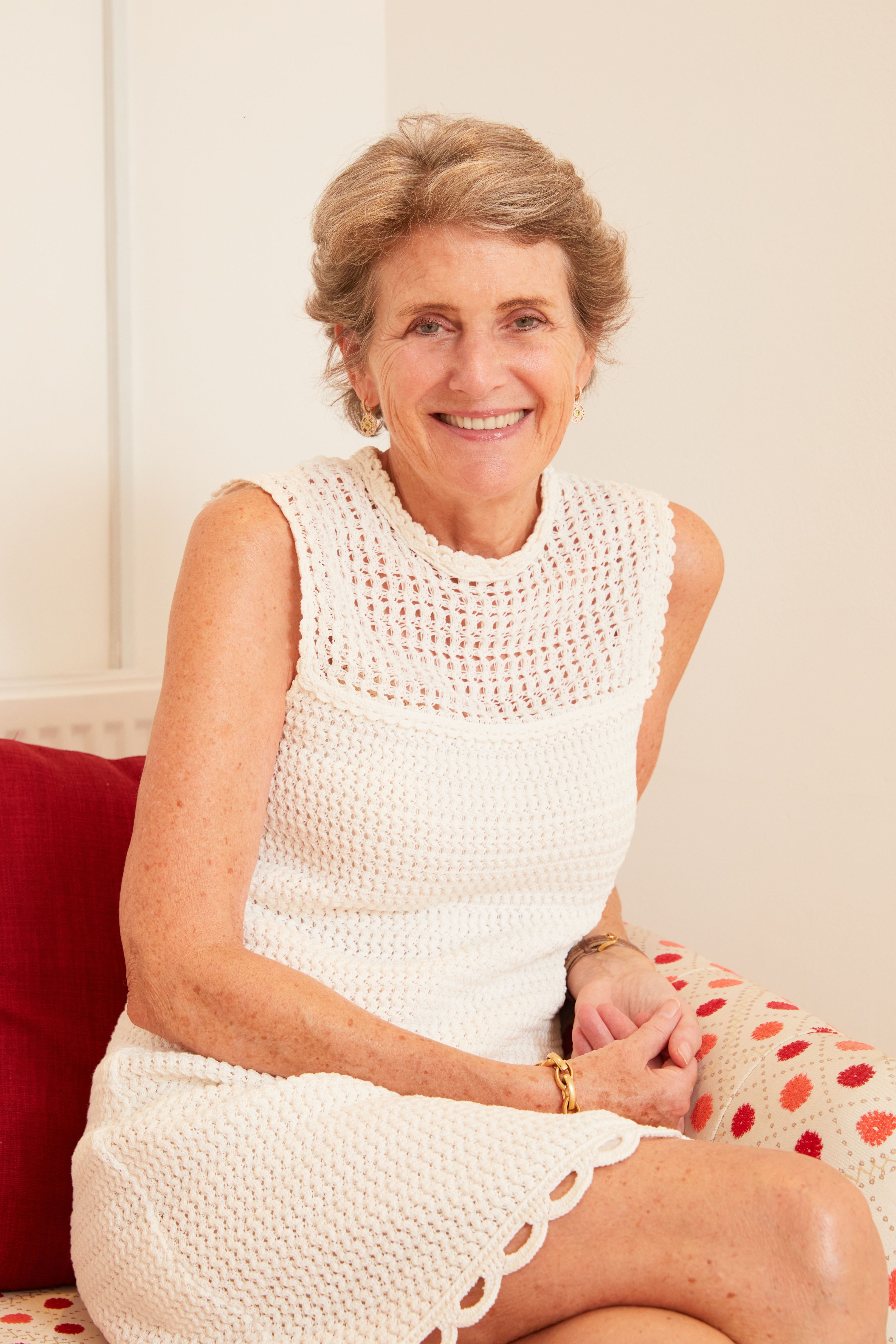 Kiki McDonough wearing a white dress sitting on a chair