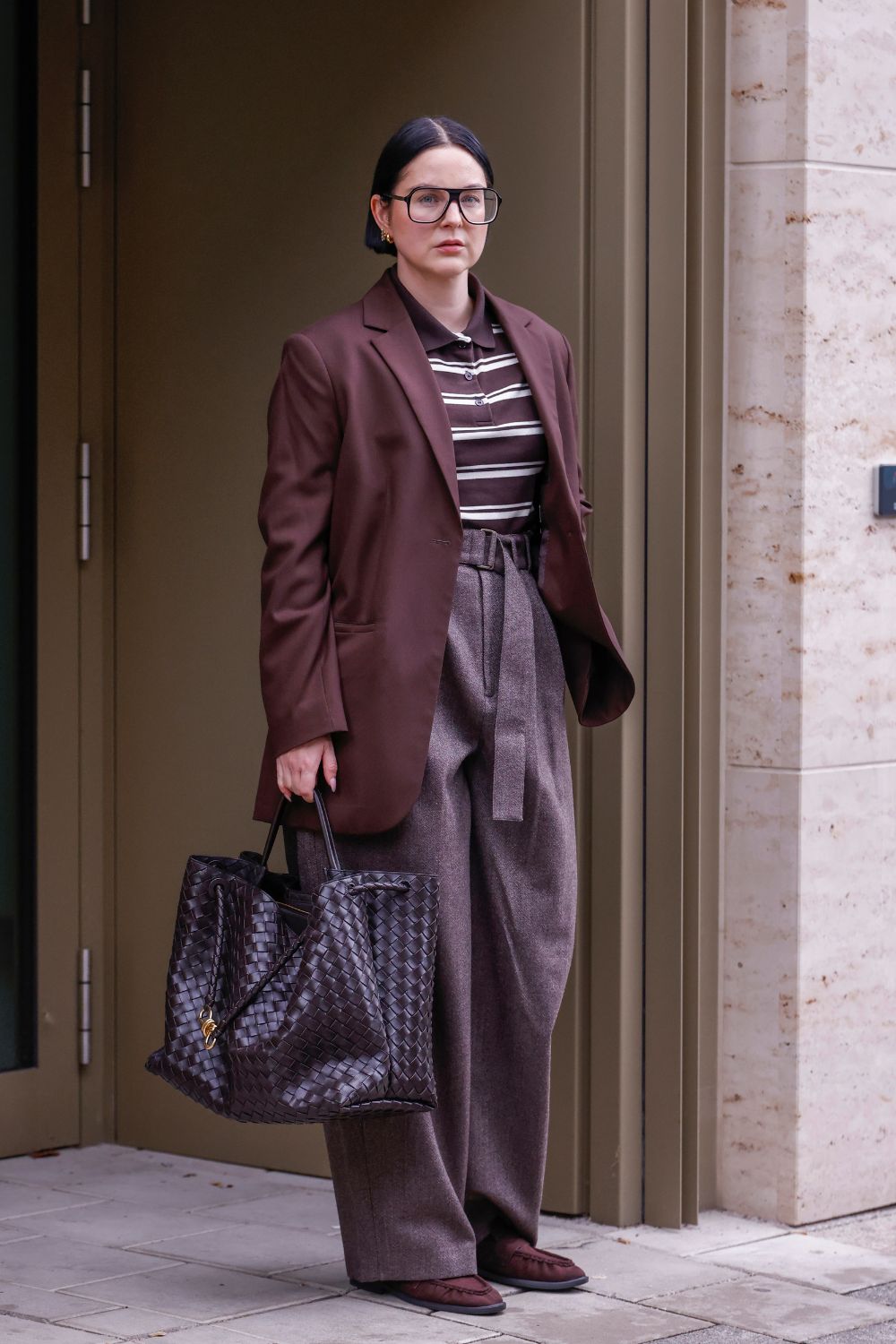 Woman wearing brown blazer, striped shirt, trousers and brown suede loafers