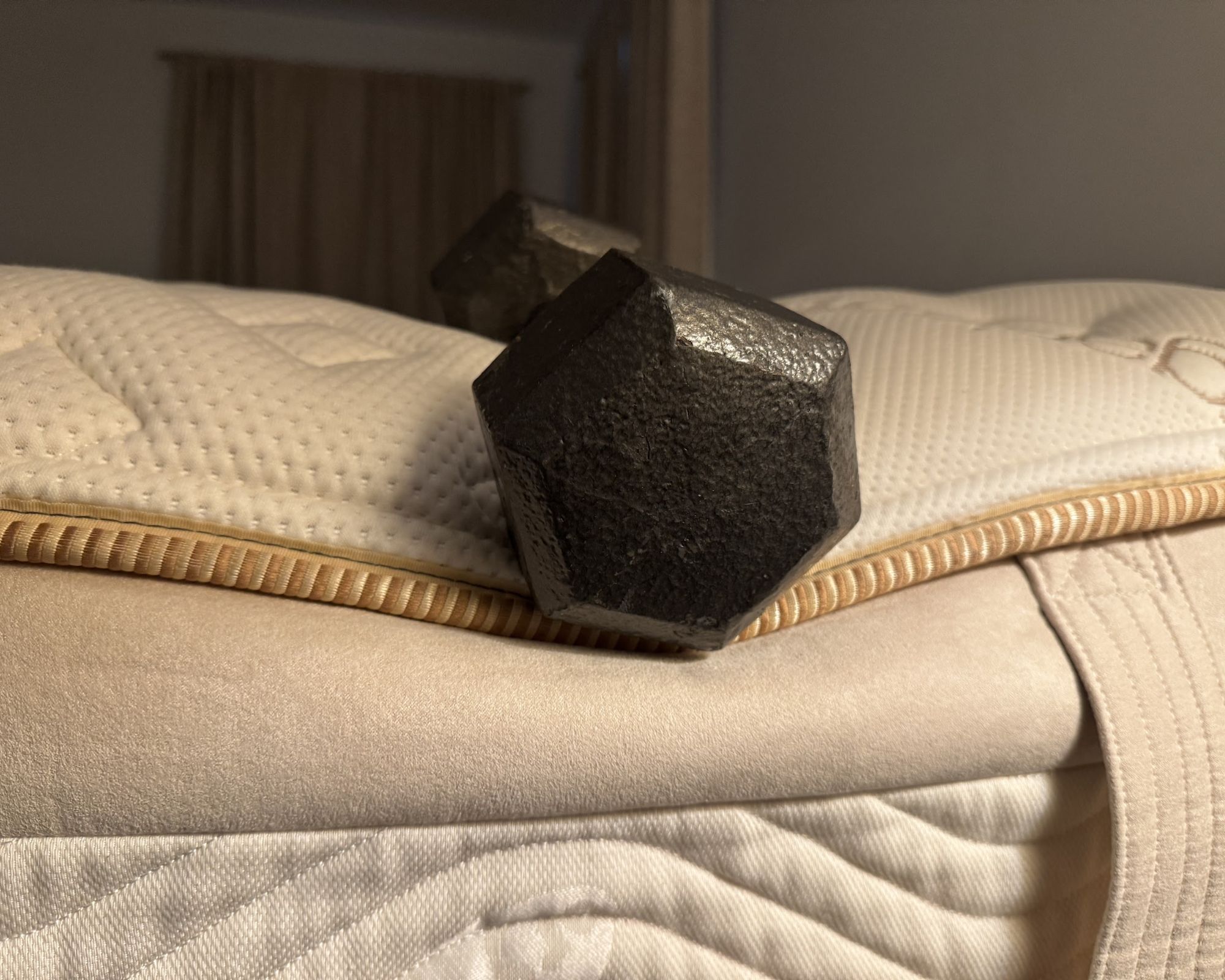 A black weight rests on the edge of the Saatva RX mattress to demonstrate edge support.