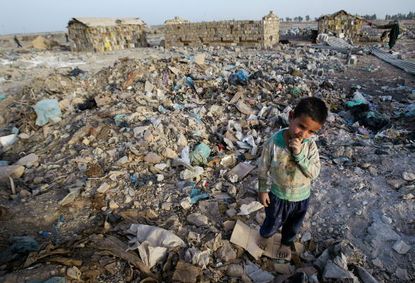An Iraqi boy stands in the dump where he lives with his family.